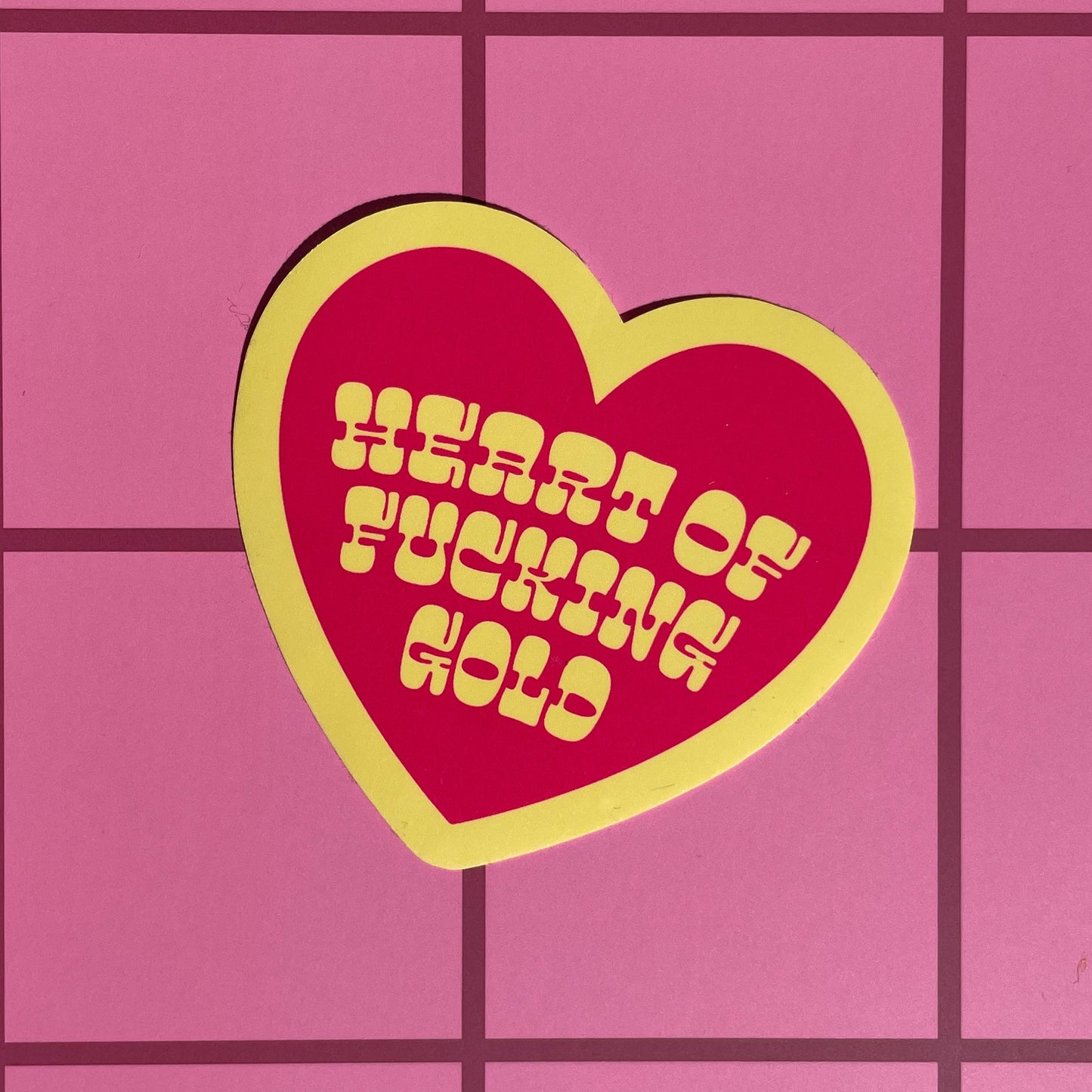 Heart-shaped sticker with text on a pink grid background
