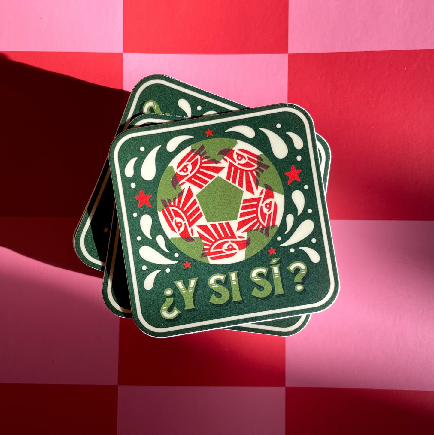 A square sticker with a red, white, and green soccer ball. A red geometric eagle pattern inside the ball, and the Spanish text '¿Y Si Sí?' in green, displayed on a pink and red checkered background.