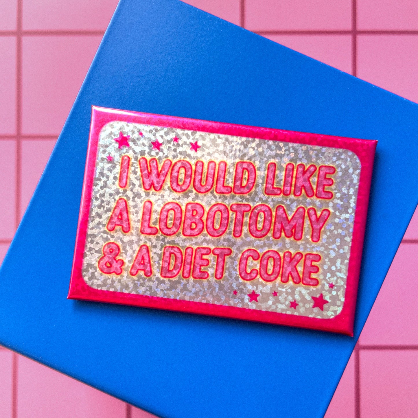 Glittery rectangle shaped magnet with pink text 'I would like a lobotomy & a diet coke' on a blue background
