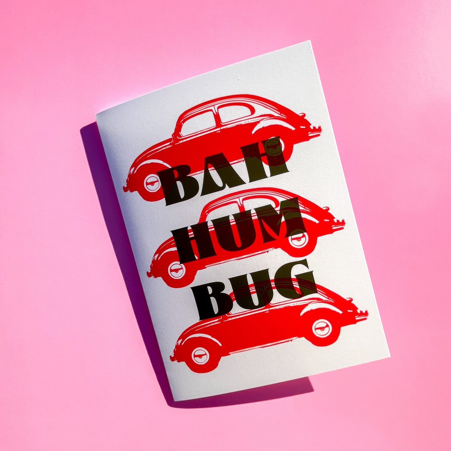 Christmas card with a VW red car illustrations and 'Bah Hum Bug' text on a pink background