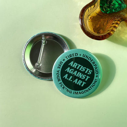 Button badge with 'Artists Against AI Art' text on a light green background