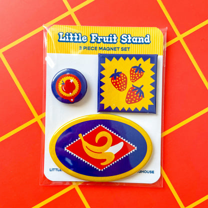 Packaged Little Fruit Stand 3-piece magnet set on a red and yellow grid background