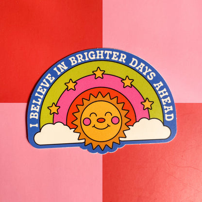 Colorful sticker with a rainbow, sun, and clouds on a red and pink checkered background