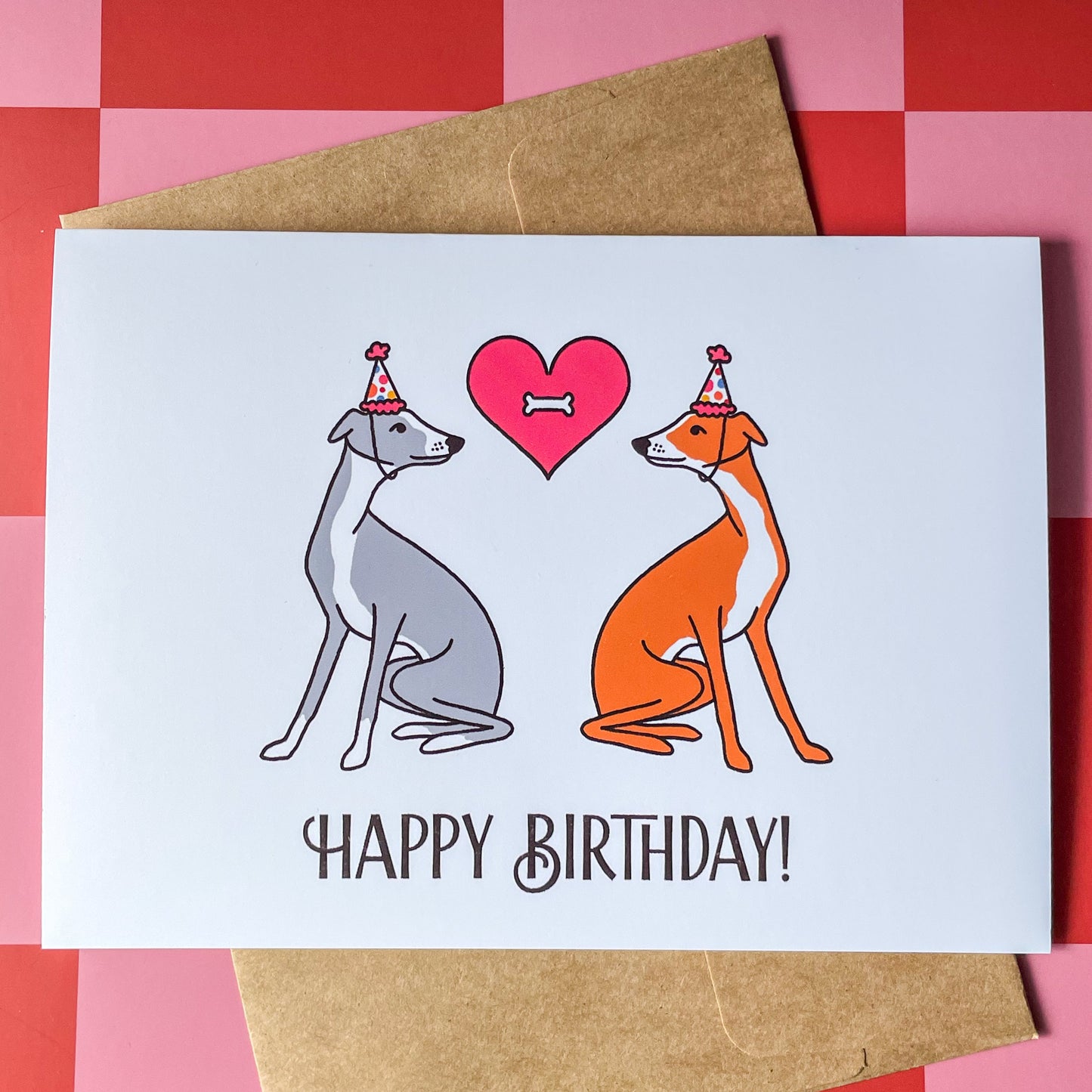 Birthday card with two italian greyhound dogs facing each other and a heart with a bone in the middle on top of a red and pink checkered background